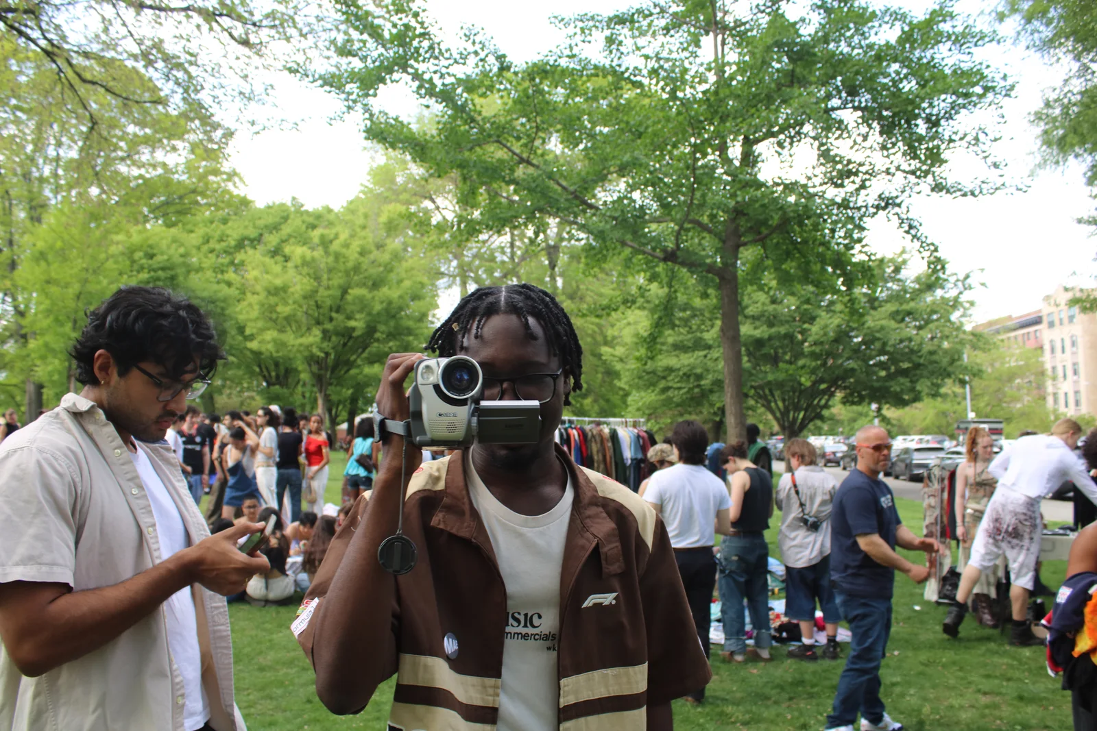 A person filming at an outdoor creative gathering.